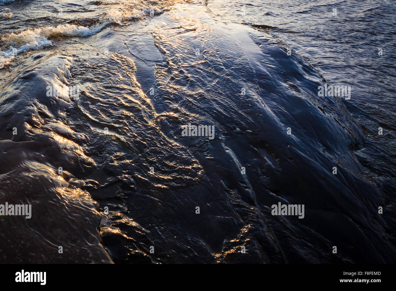Eis, Felsen und Wellen im Sonnenlicht Stockfoto