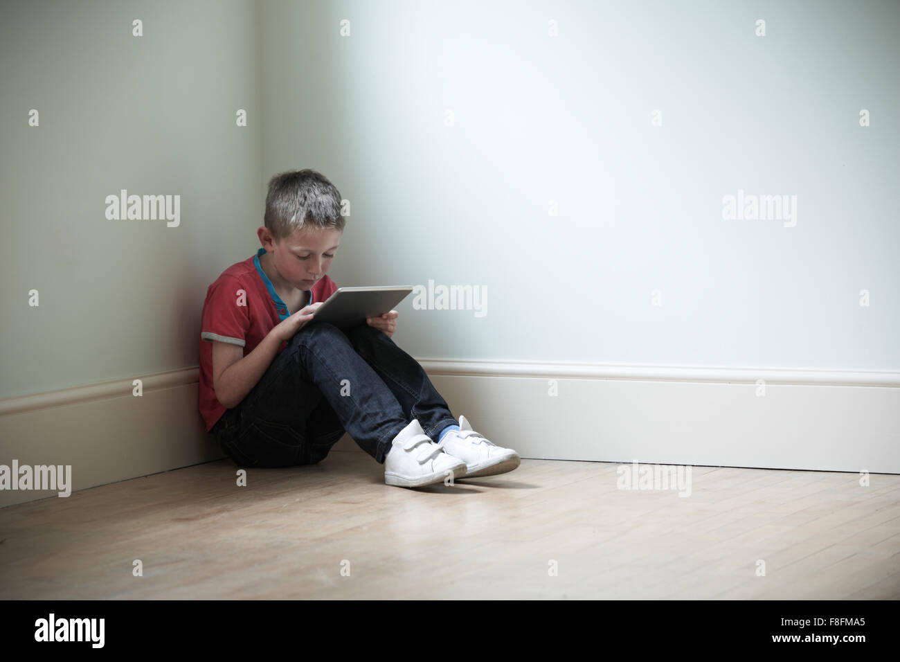 Unglückliches Kind im Zimmer mit Digital-Tablette Stockfoto