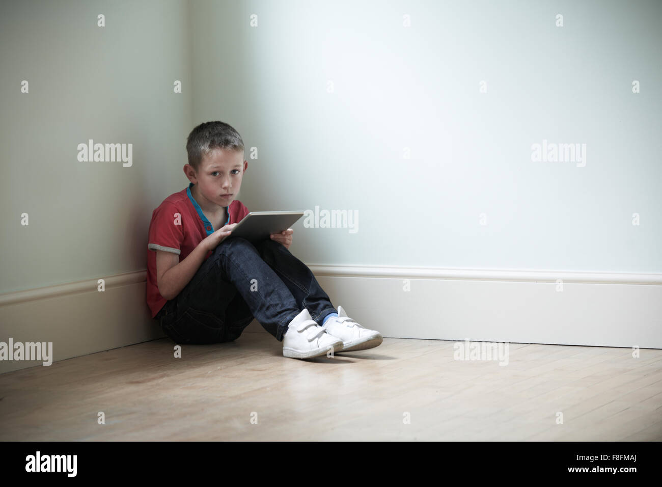 Unglückliches Kind im Zimmer mit Digital-Tablette Stockfoto