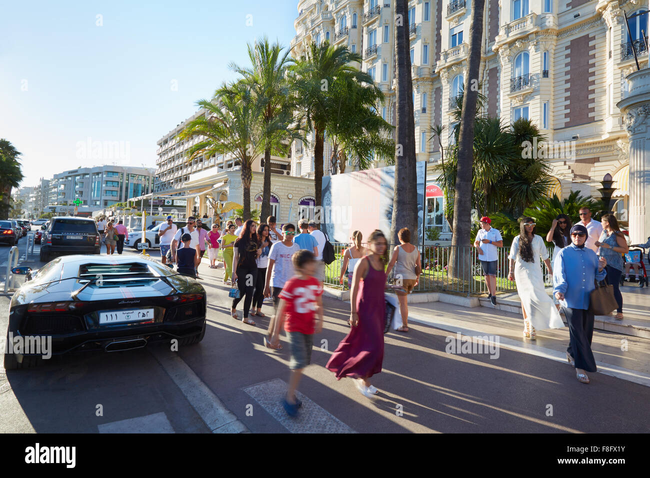 Menschen zu Fuß in einem Sommernachmittag an der Strandpromenade Croisette in Cannes in der Nähe von Intercontinental Carlton Hotel und Luxus Auto Stockfoto