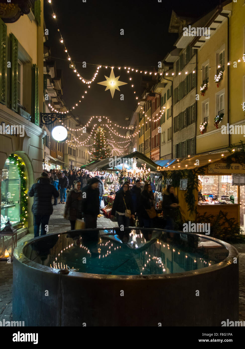 Weihnachtsmarkt nach Einbruch der Dunkelheit in der Marktgasse, Bremgarten, Kanton Aargau, Schweiz beschäftigt. Stockfoto
