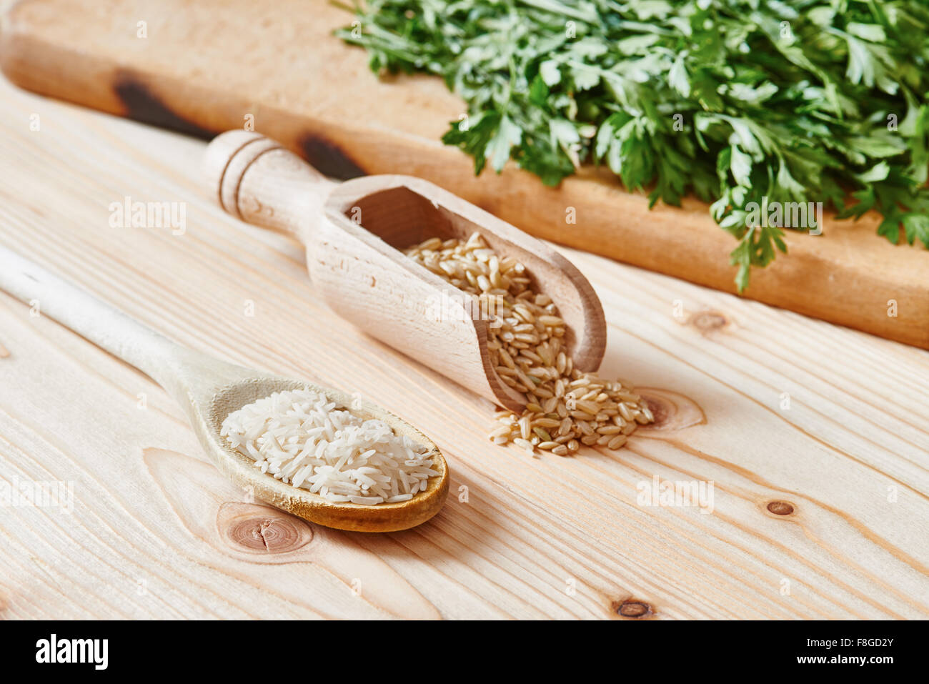 Basmati-Reis und brauner Reis auf Löffel auf leichte Holztisch gelegt Stockfoto