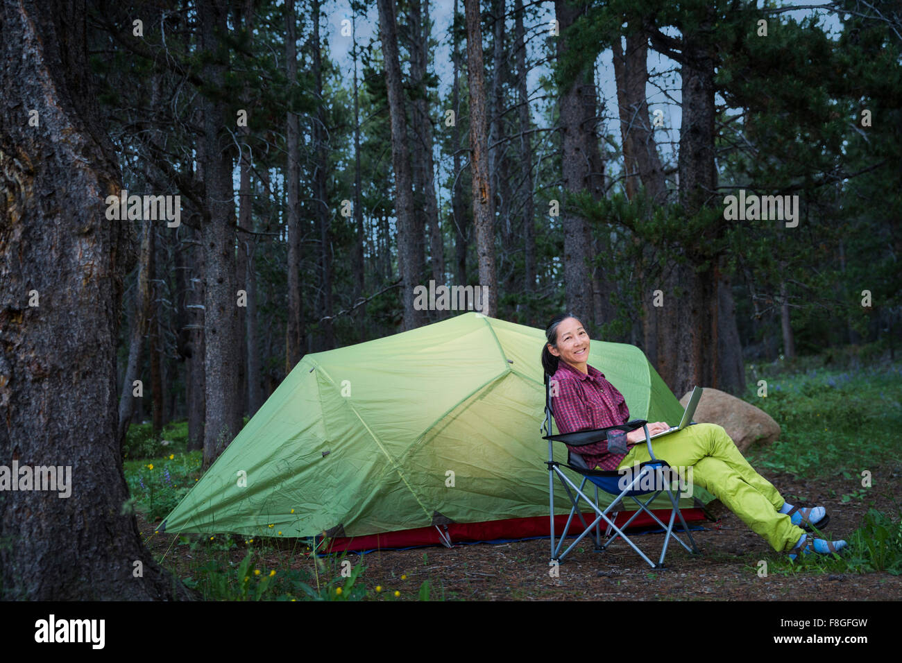 Japanische Frau mit Laptop am Campingplatz Stockfoto