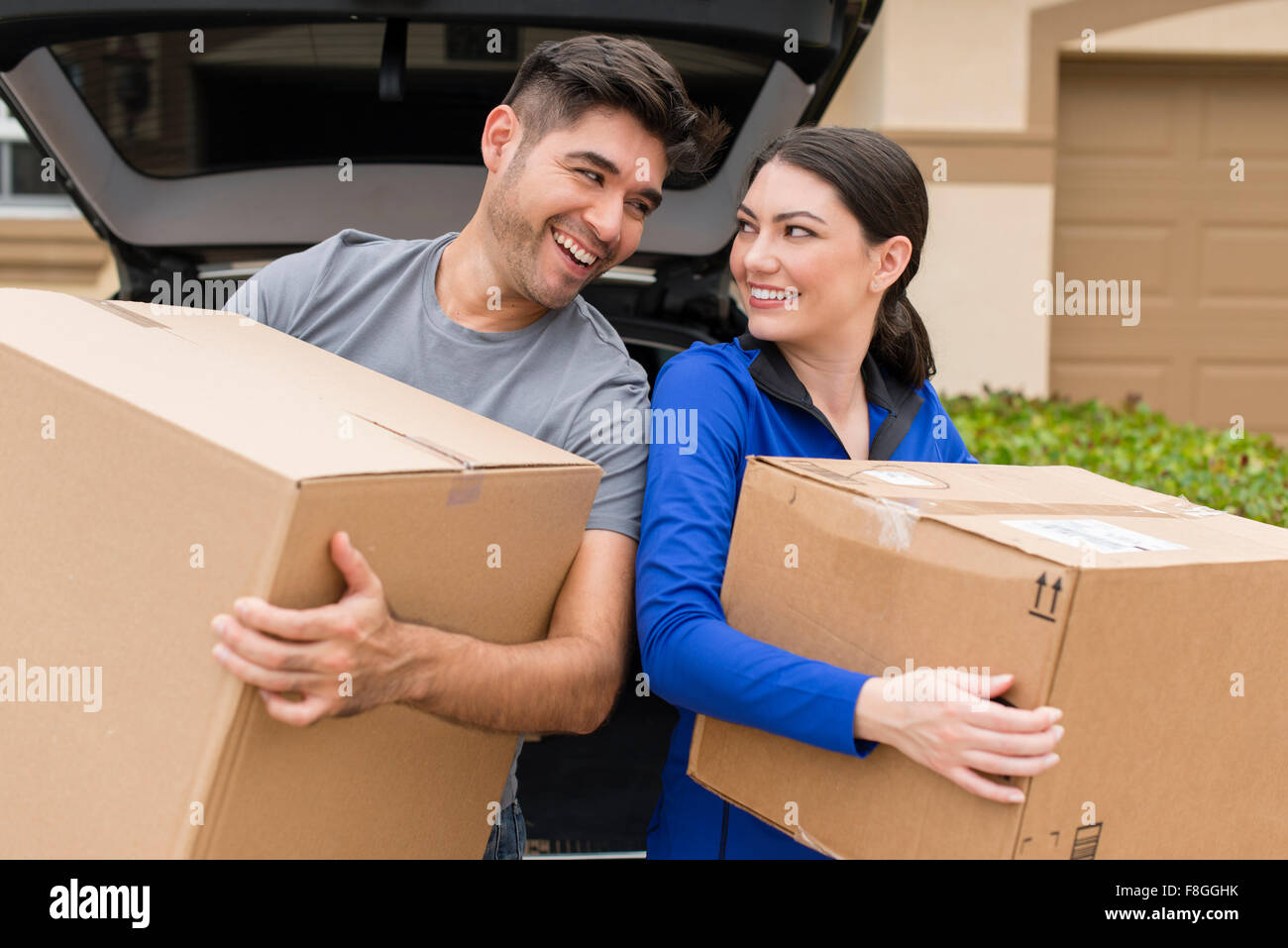 Hispanische paar tragen Kartons in der Nähe von Auto Stockfoto