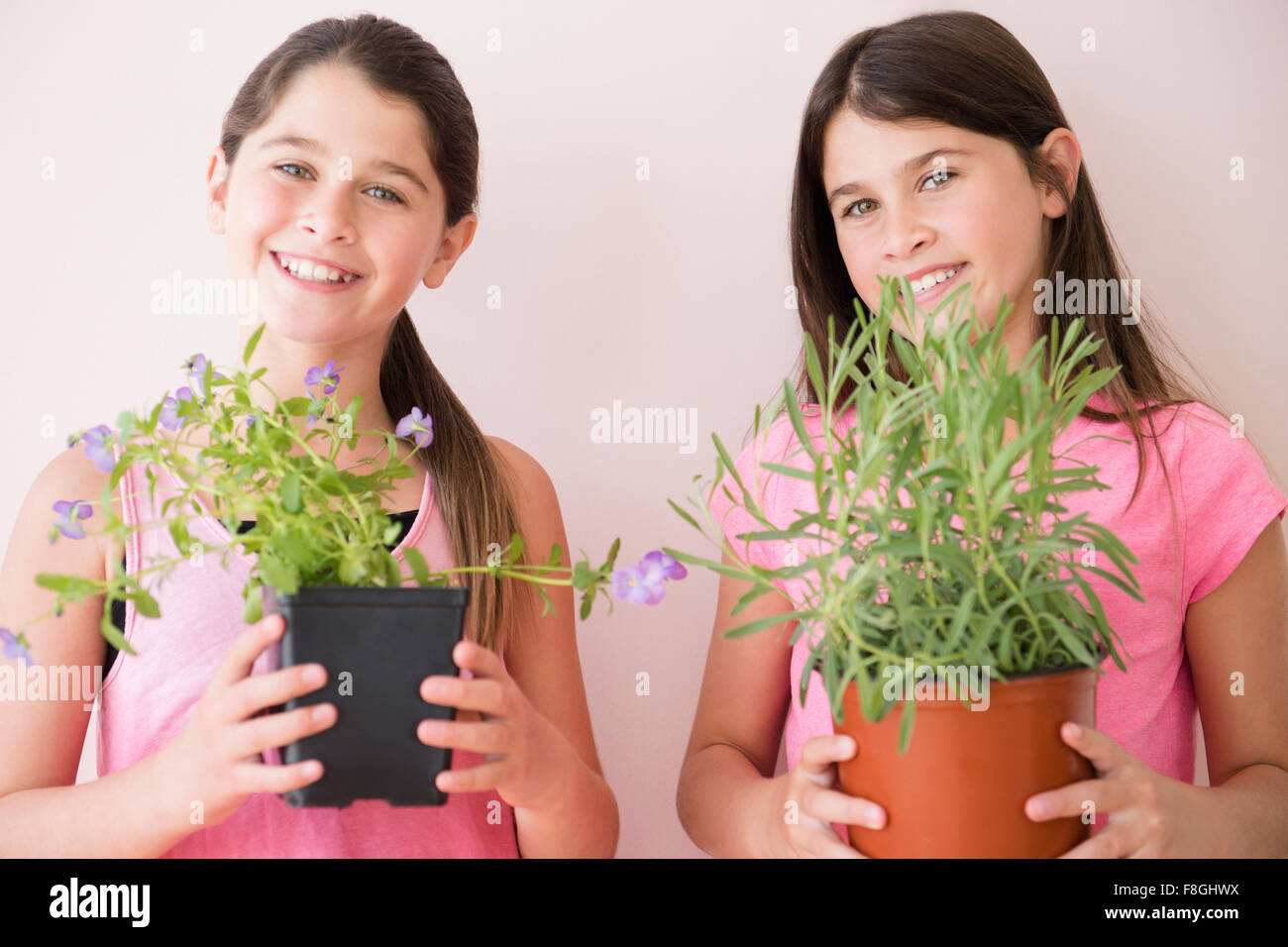 Kaukasische Zwillingsschwestern hält Topfpflanzen Stockfoto