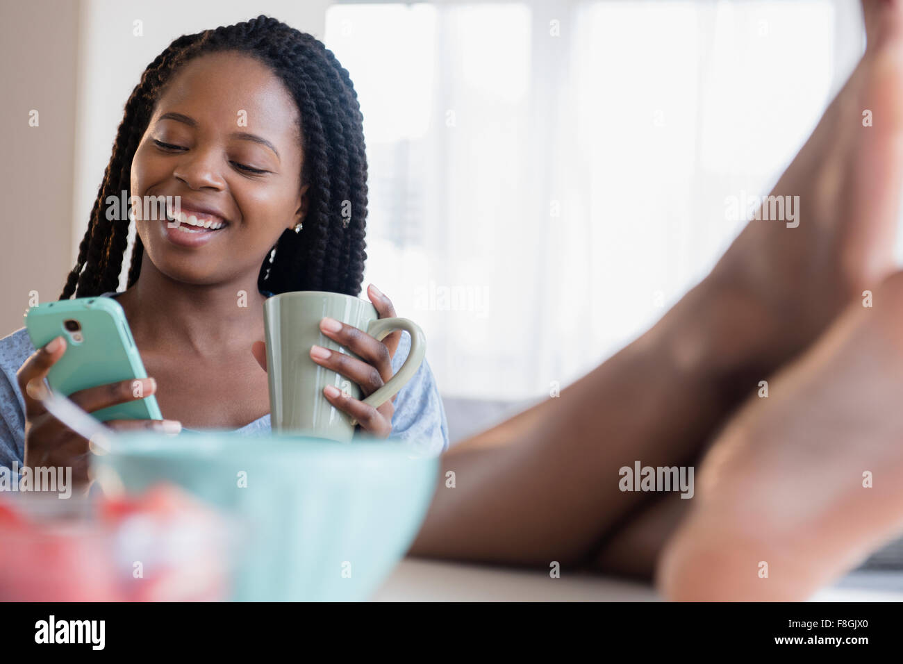 Schwarze Frau mit Handy und Kaffee trinken Stockfoto