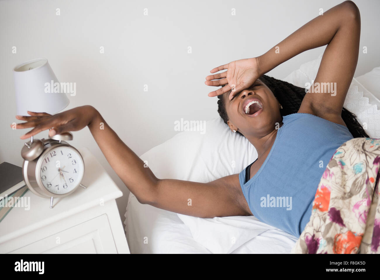 Schwarze Frau mit Wecker aufwachen Stockfoto