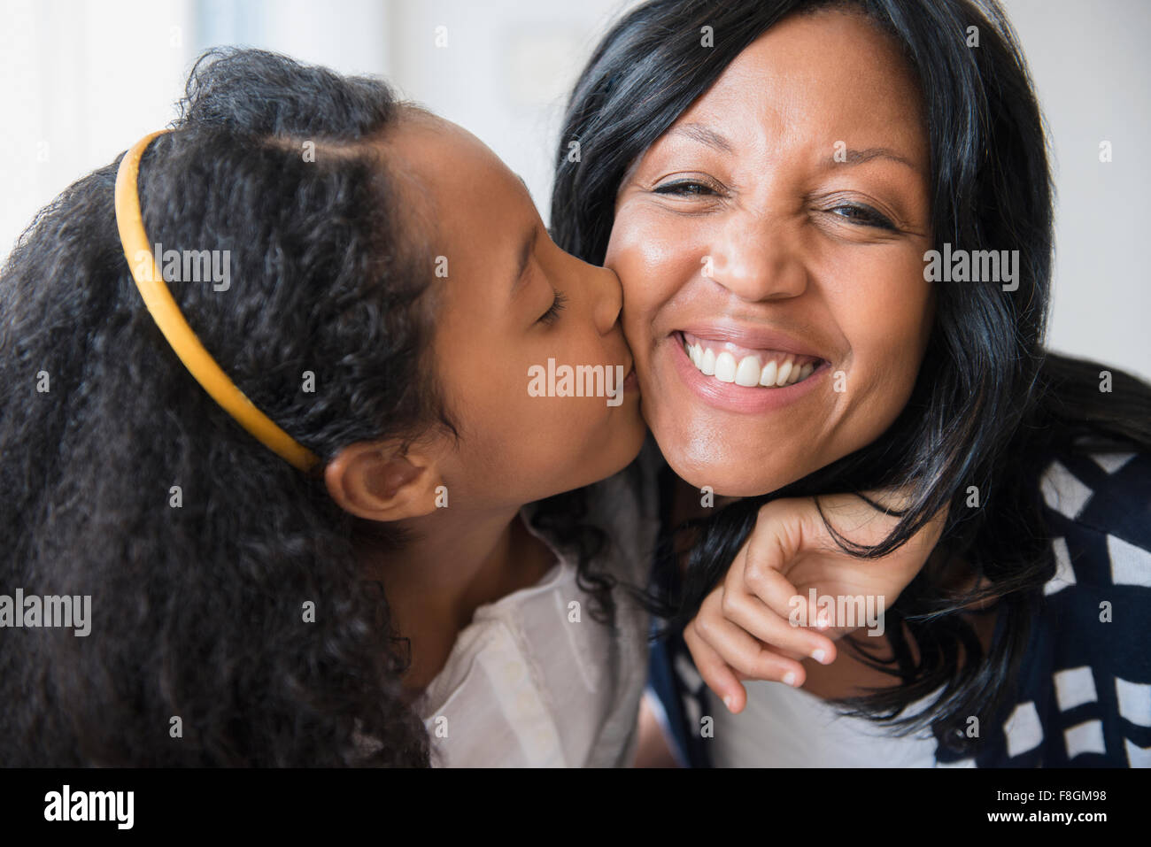 Mädchen küssen lächelnde Mutter Stockfoto