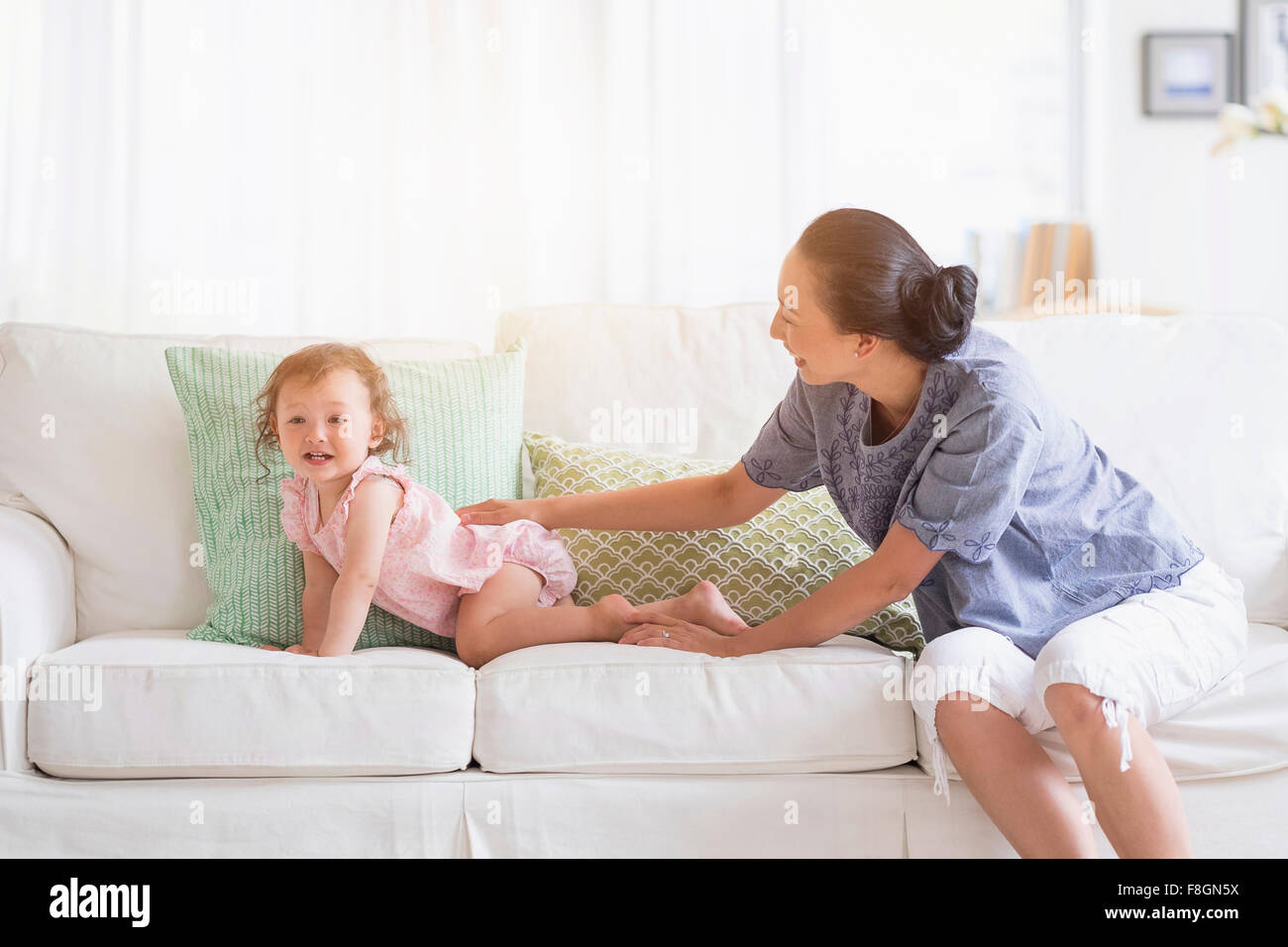 Mutter und Baby Tochter spielen auf sofa Stockfoto