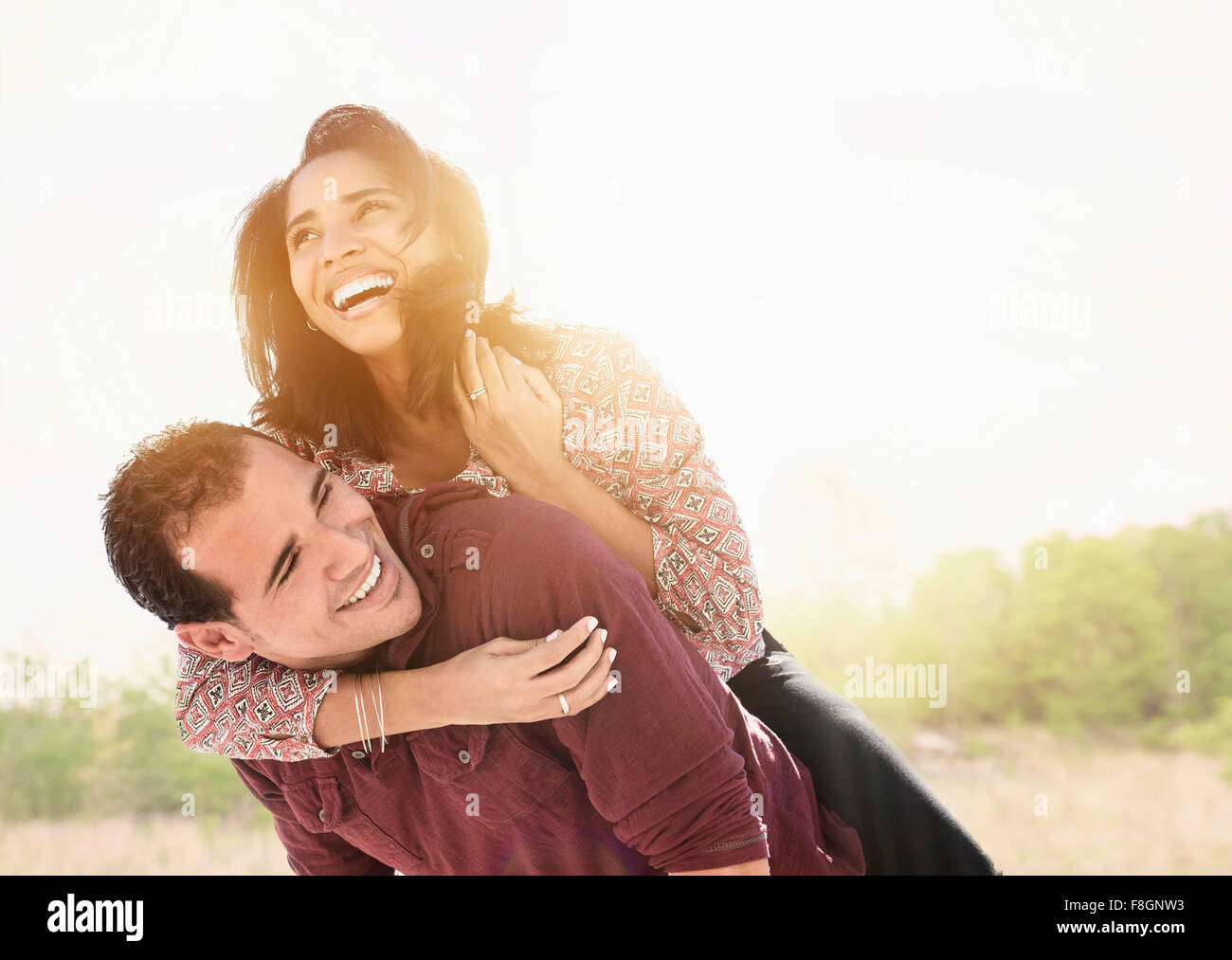 Hispanic Mann mit Freundin Huckepack Stockfoto