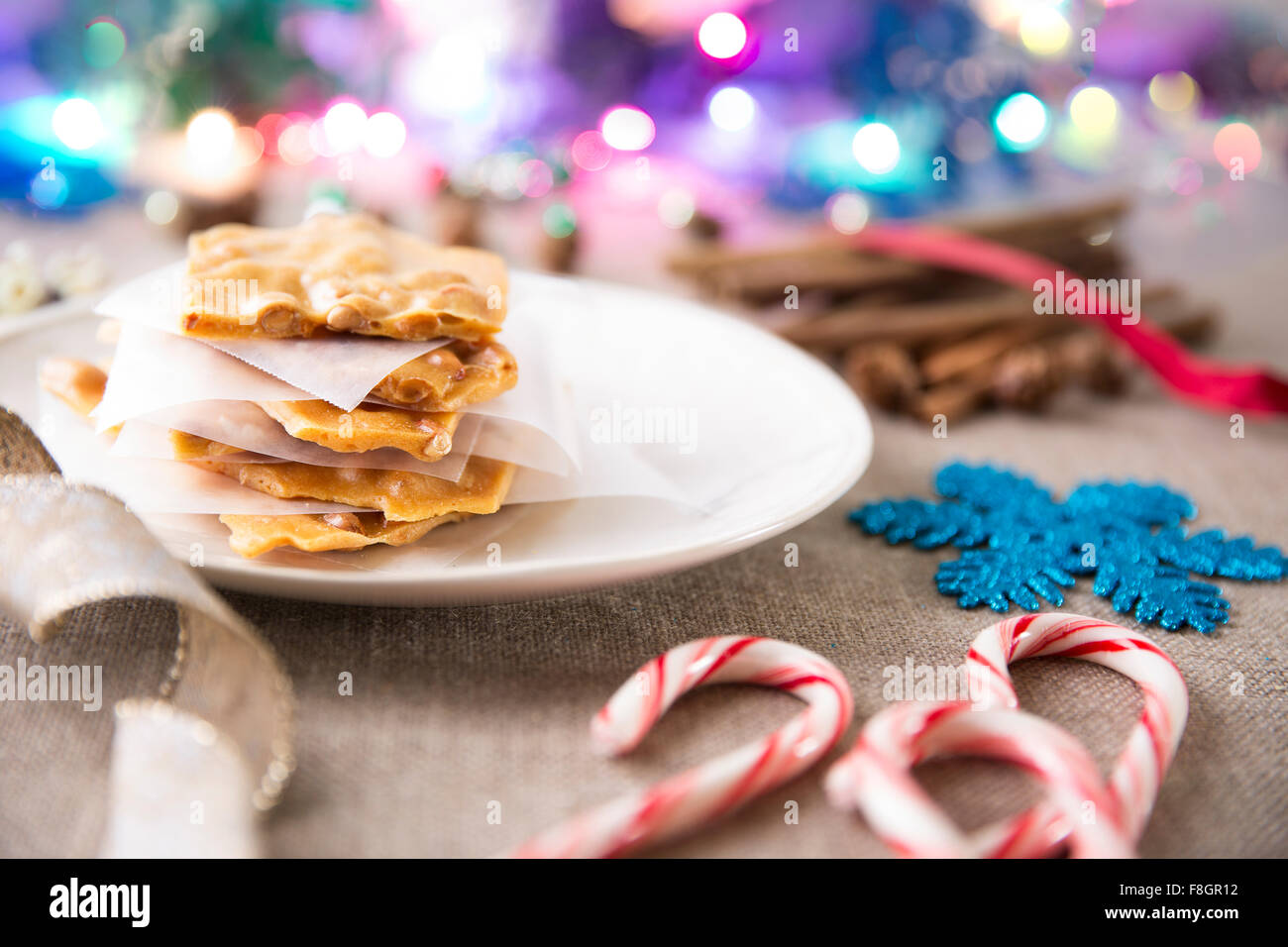Festliche Szene mit Erdnusskrokant auf eine Platte und Candy Canes und anderen Weihnachtsschmuck Stockfoto