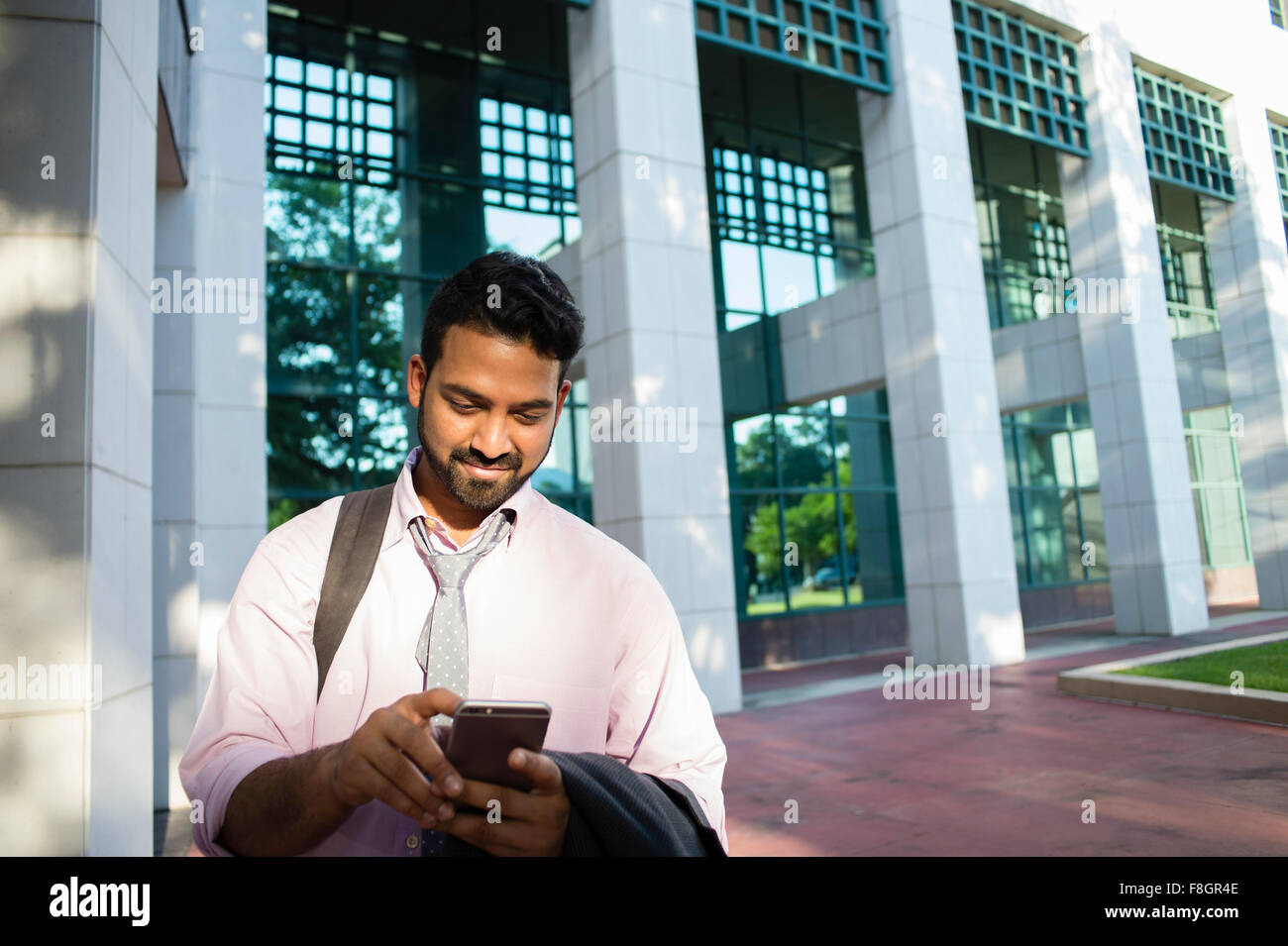 Indischer Geschäftsmann mit Handy vor Bürogebäude Stockfoto