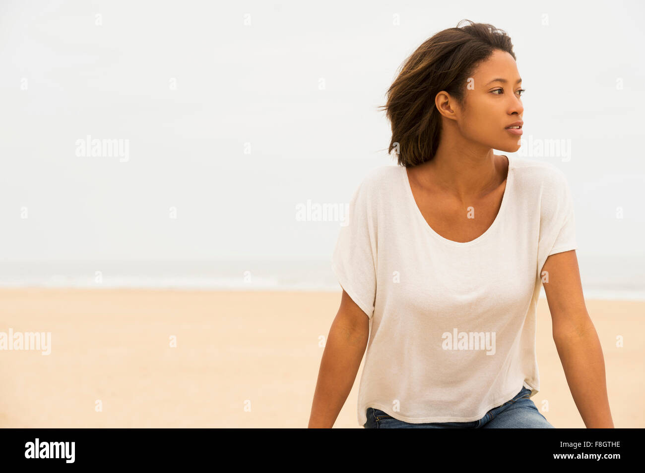 Nachdenklich afroamerikanische Frau sitzt am Strand Stockfoto