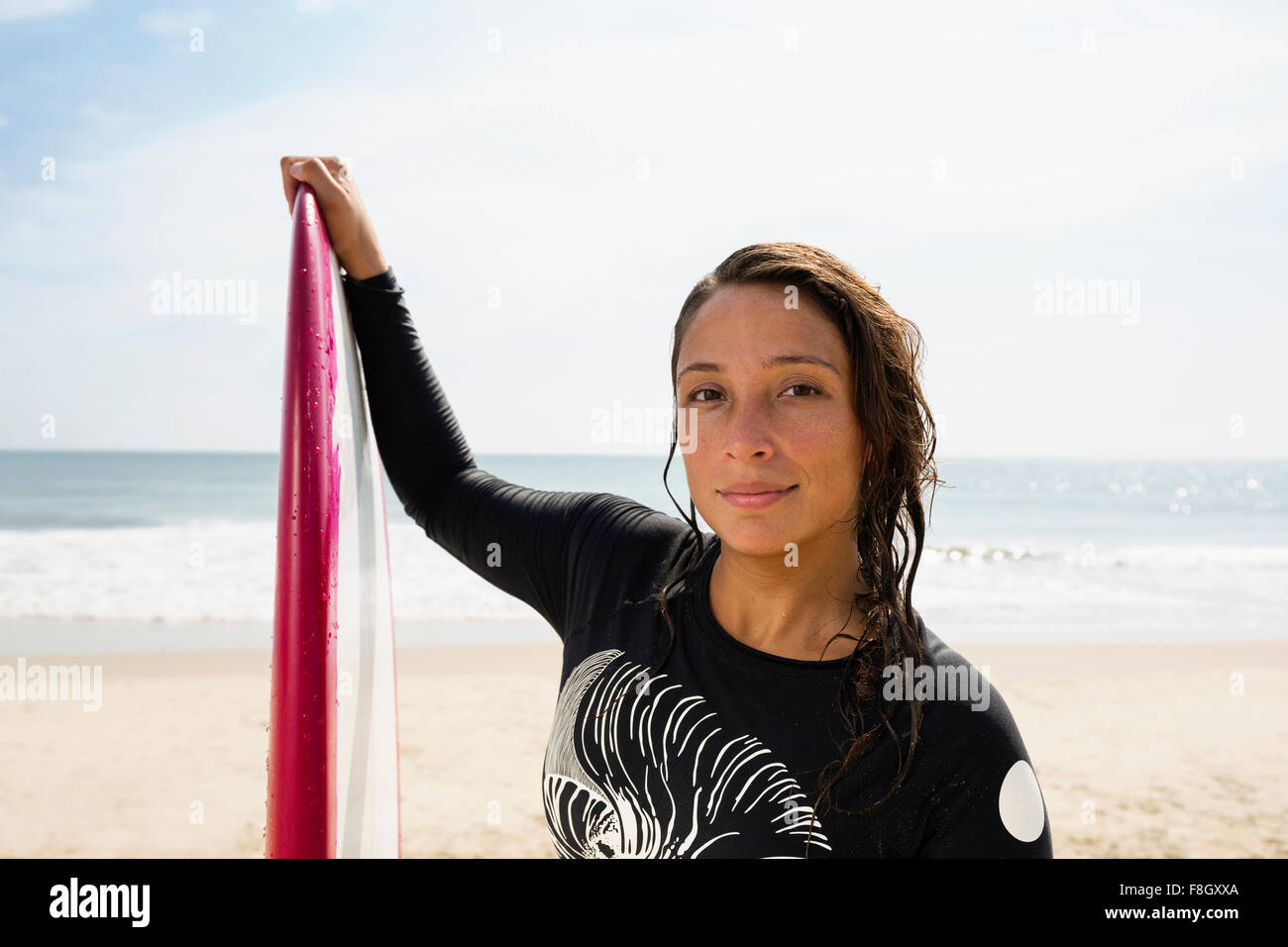 Hispanische Surfer mit Surfbrett am Strand Stockfoto