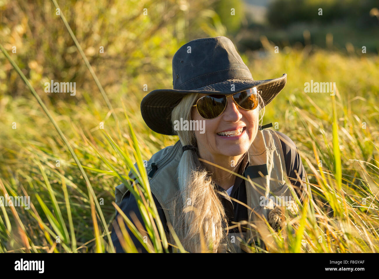 Kaukasische Frau lächelnd in hohe Gräser Stockfoto