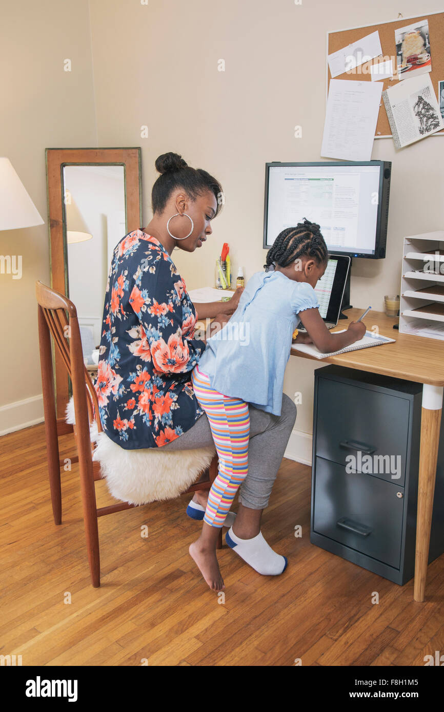 African American Mutter mit Tochter von zu Hause aus arbeiten Stockfoto
