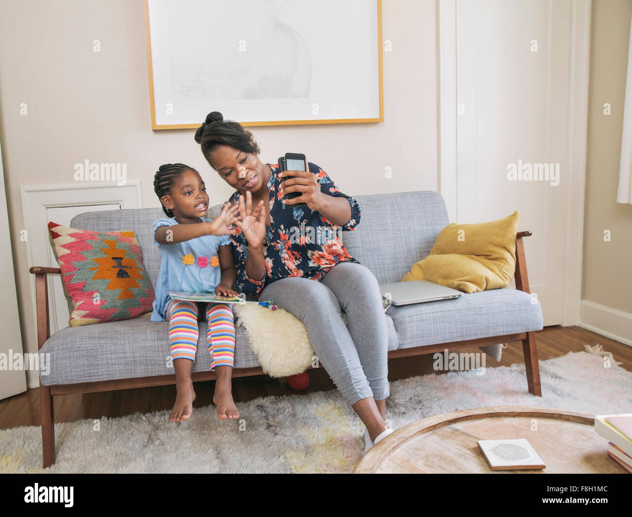 African American Mutter und Tochter nehmen Selfie im Wohnzimmer Stockfoto