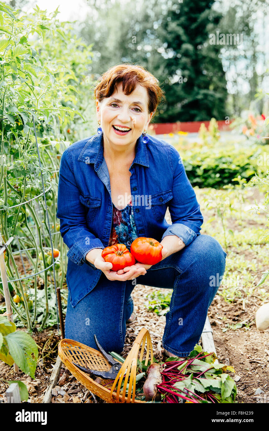 Kaukasische Frau mit Tomaten im Garten Stockfoto
