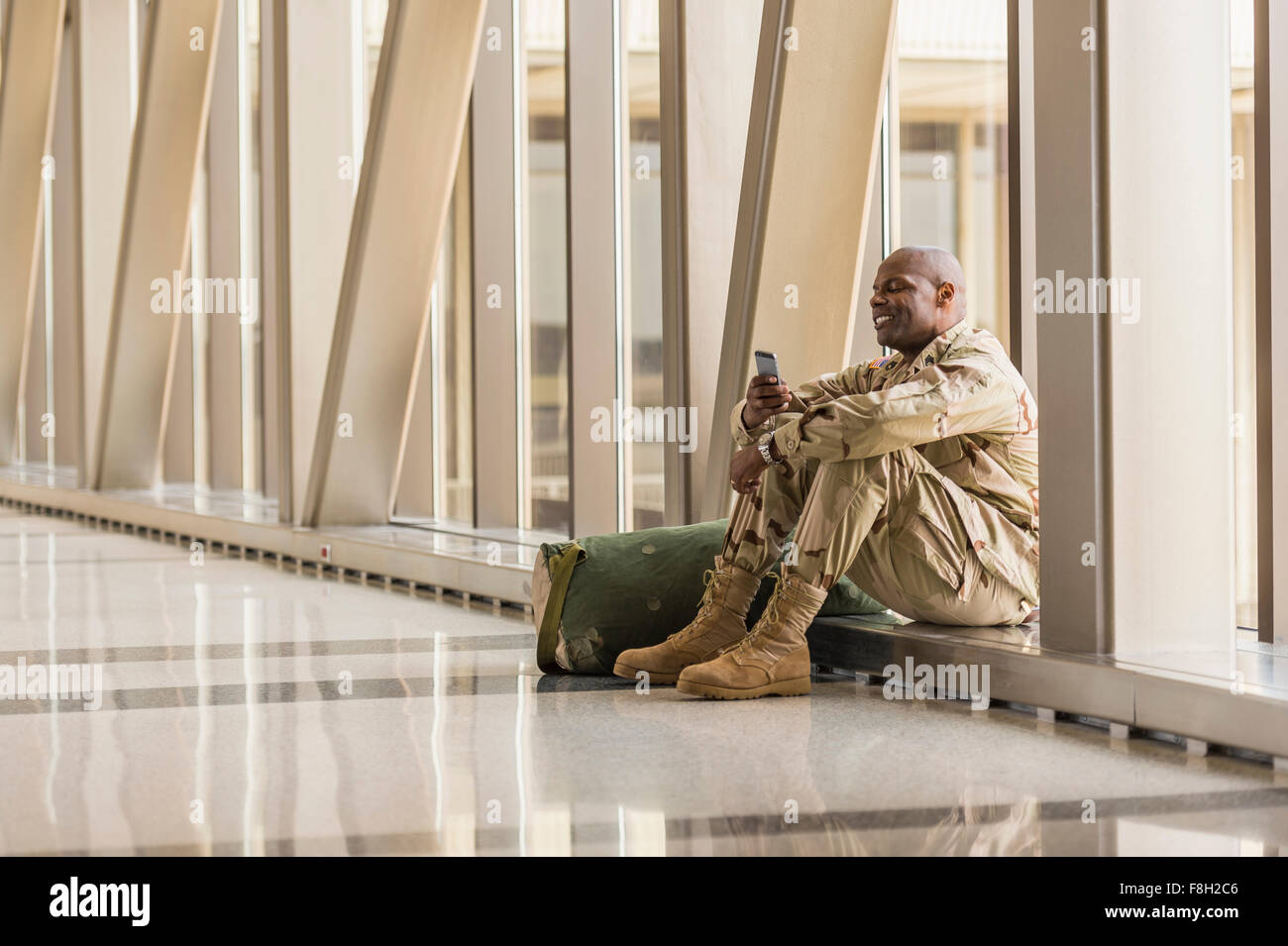 Afrikanische amerikanische Soldaten mit Handy im Flughafen Stockfoto