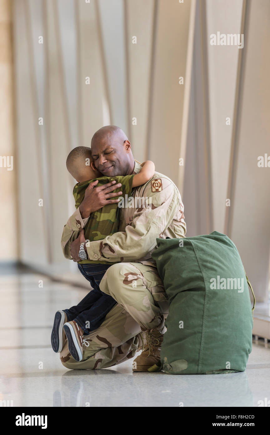 Afrikanische amerikanische Soldat umarmt Sohn im Flughafen Stockfoto