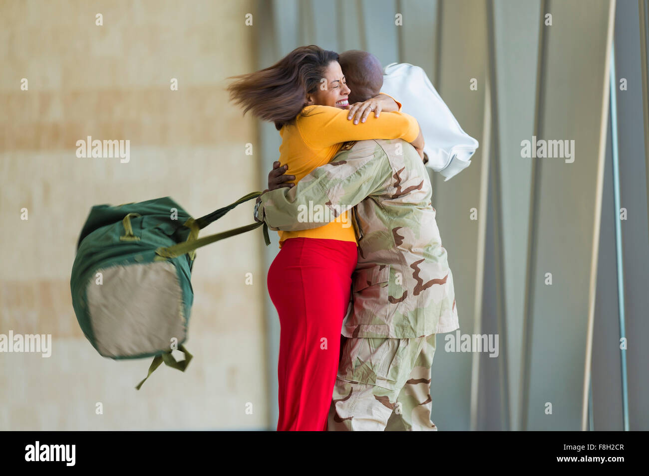 Afrikanische amerikanische Soldat umarmt Frau im Flughafen Stockfoto