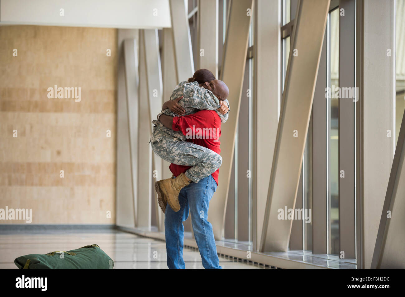 Afrikanische amerikanische Soldat umarmt Mann im Flughafen Stockfoto