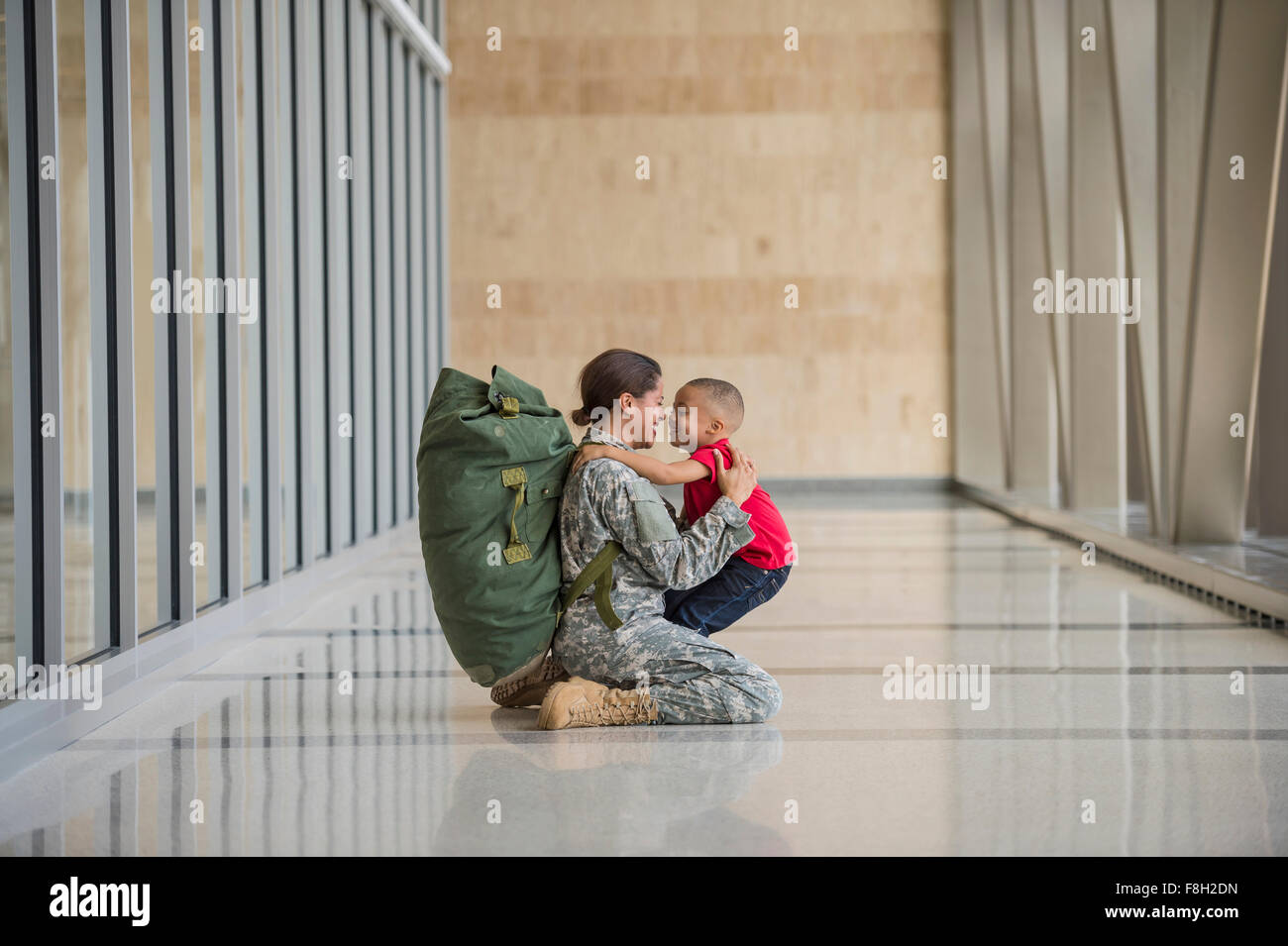 Afrikanische amerikanische Soldat umarmt Sohn im Flughafen Stockfoto