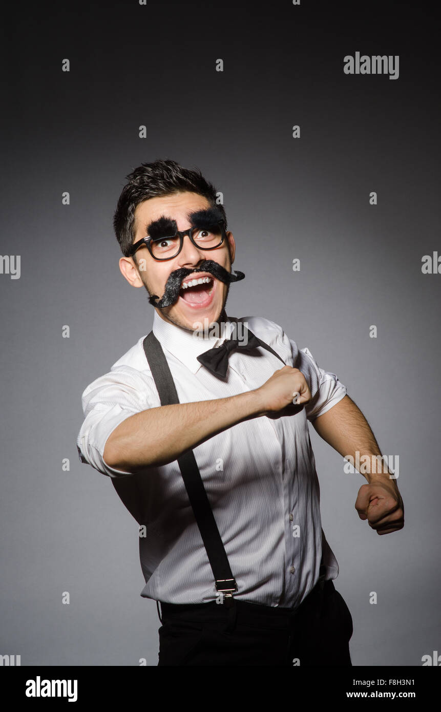 Junger Mann mit falschen Schnurrbart isoliert auf grau Stockfoto