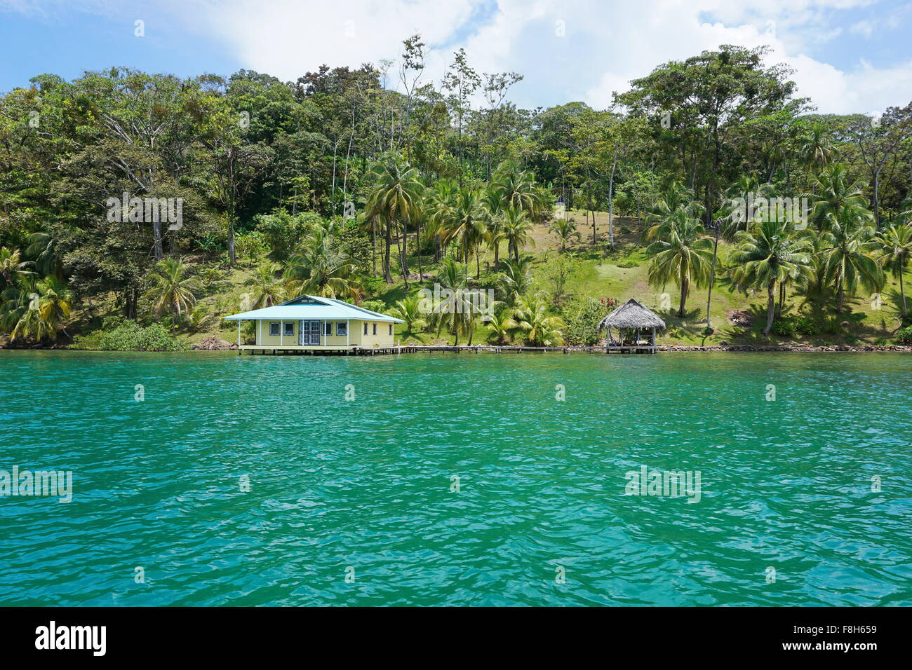 Seegrundstück mit tropischer Vegetation und Haus mit Hütte über dem Wasser, betrachtet aus dem Meer, Karibik, Panama Stockfoto