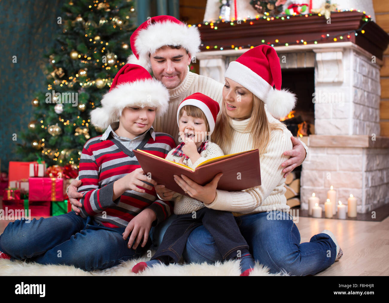 Fröhliche Familie von vier Personen zusammen am Heiligen Abend lesen Stockfoto