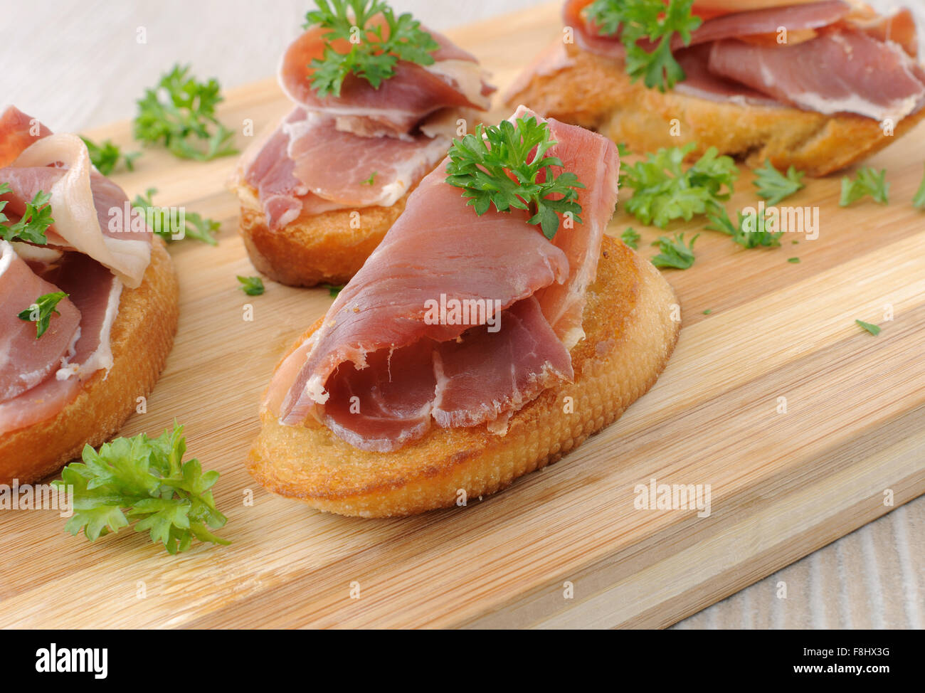 Brotscheiben mit spanischen Jamon Serrano auf einem Holzbrett Stockfoto