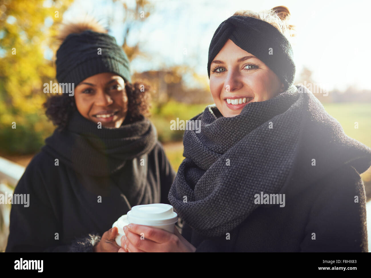 Zwei Freundinnen Blick in die Kamera und lächelnd halten Kaffee zu gehen Stockfoto