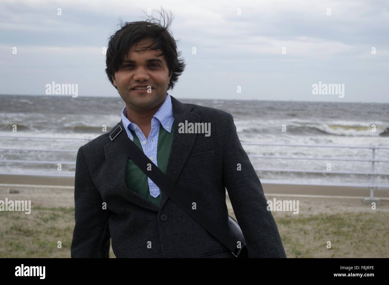 Ein Geschäftsmann am Strand in der Nähe von Meer mit starkem wind Stockfoto