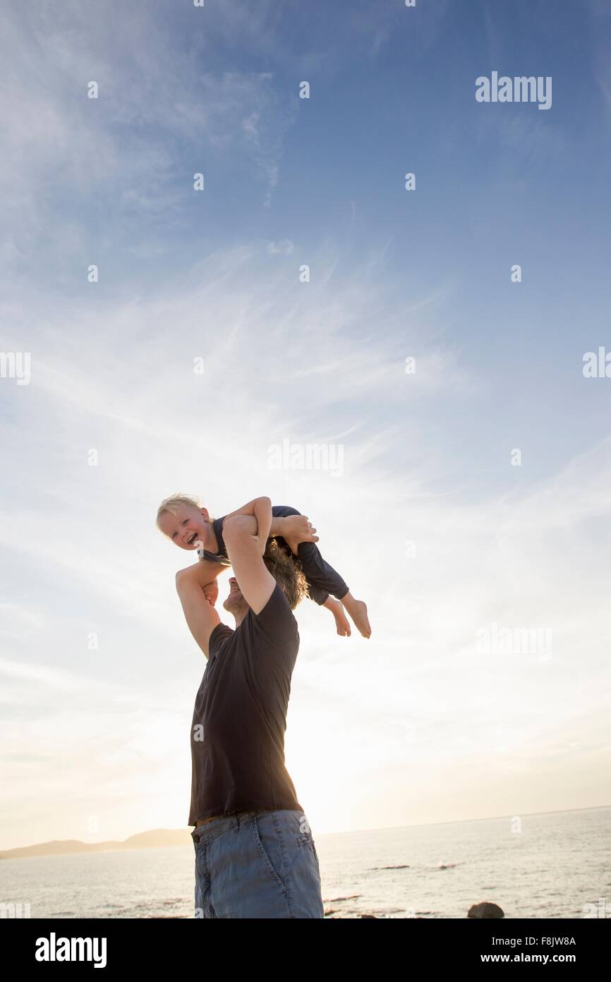 Reifer Mann hob seine Kleinkind Tochter am Strand, Calvi, Korsika, Frankreich Stockfoto