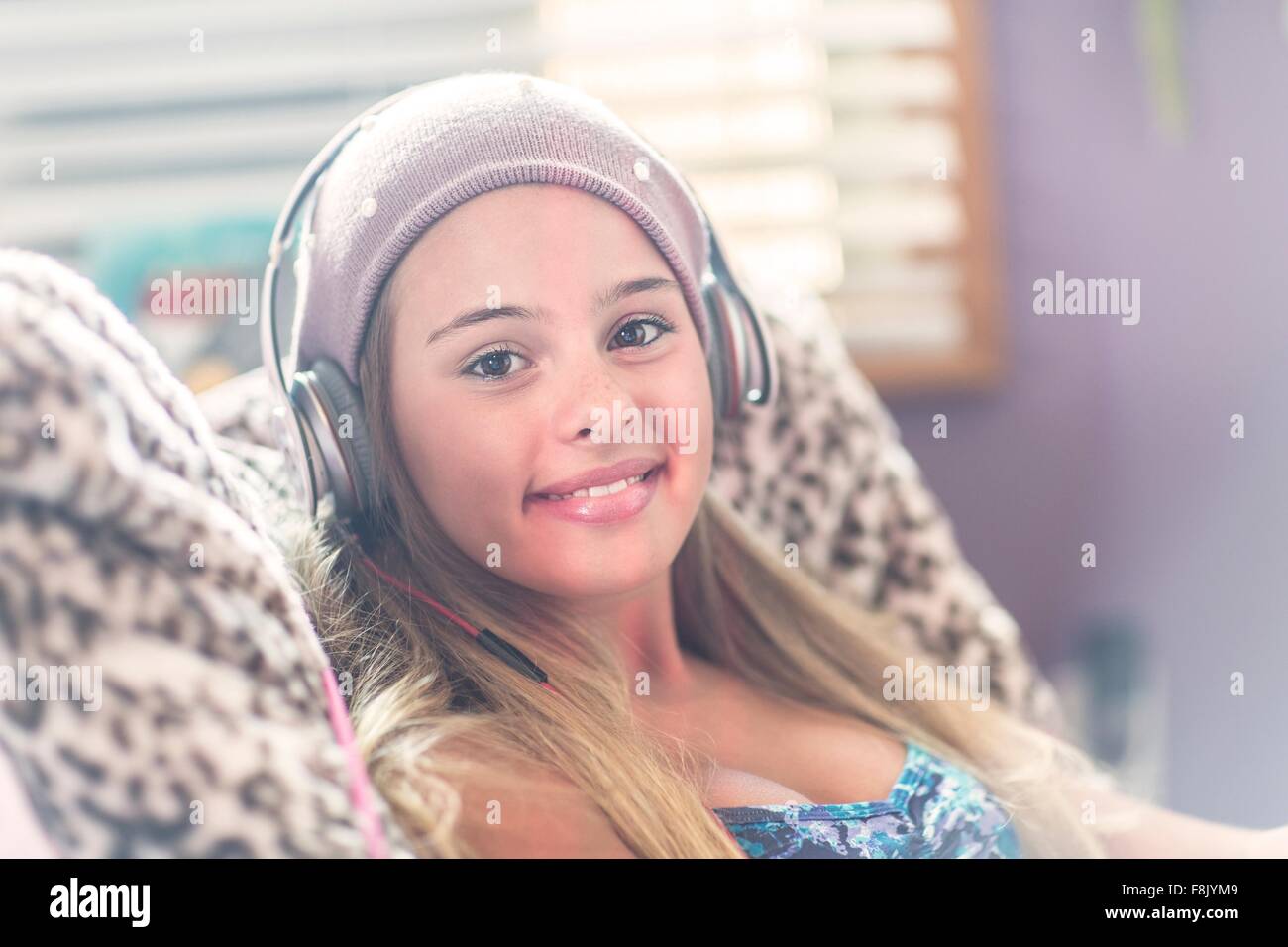 Teenager mit Kopfhörer lächelnd auf Sessel Stockfoto