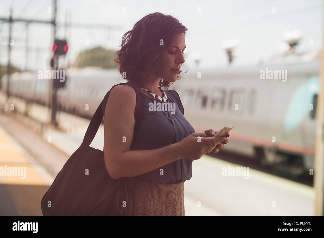 Mitte erwachsenen Frau wartet am Bahnhof, mit smartphone Stockfoto