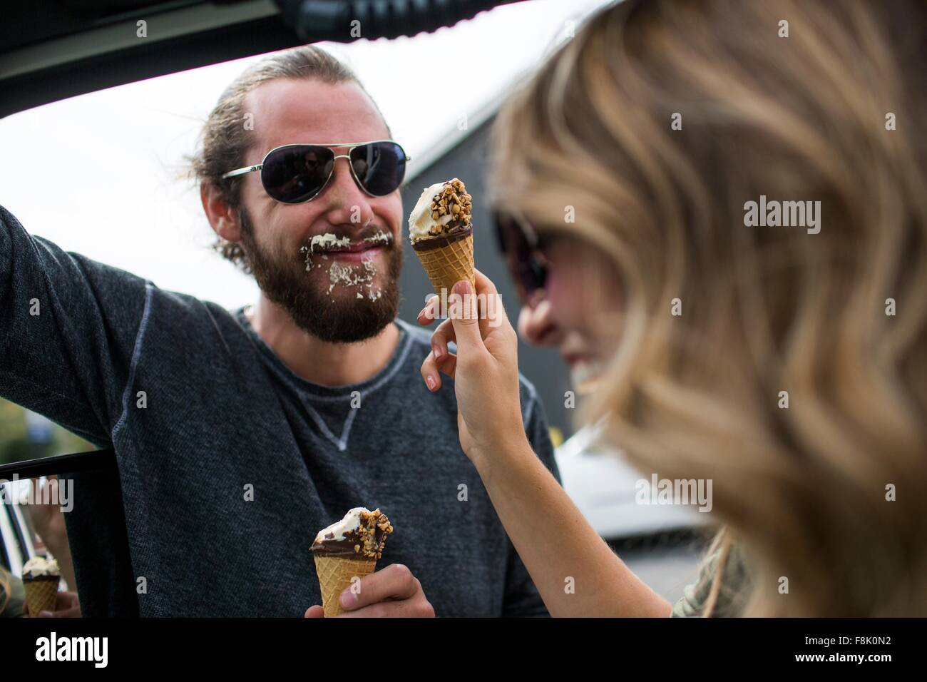 Junges Paar neben Jeep messily essen Eiscreme-Kegel Stockfoto