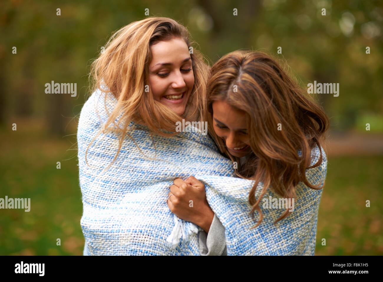 Zwei junge Freundinnen eingehüllt in blaue Decke im park Stockfoto