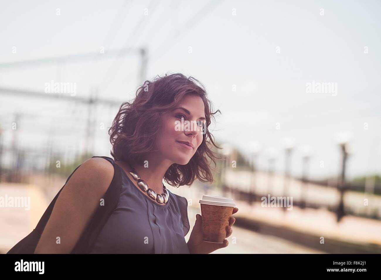 Mitte erwachsenen Frau wartet am Bahnhof halten Kaffeetasse Stockfoto