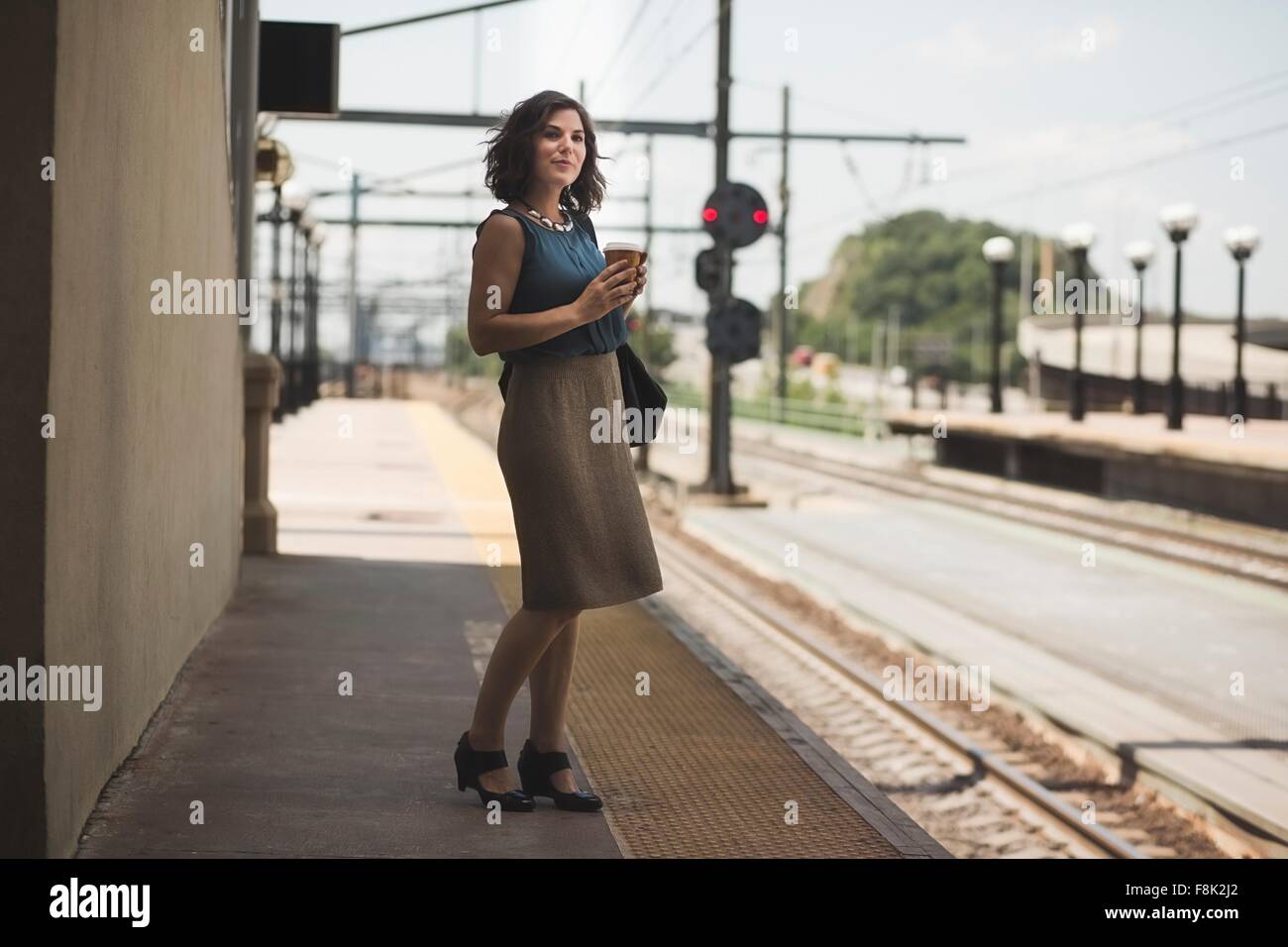 Mitte erwachsenen Frau wartet am Bahnhof halten Kaffeetasse Stockfoto