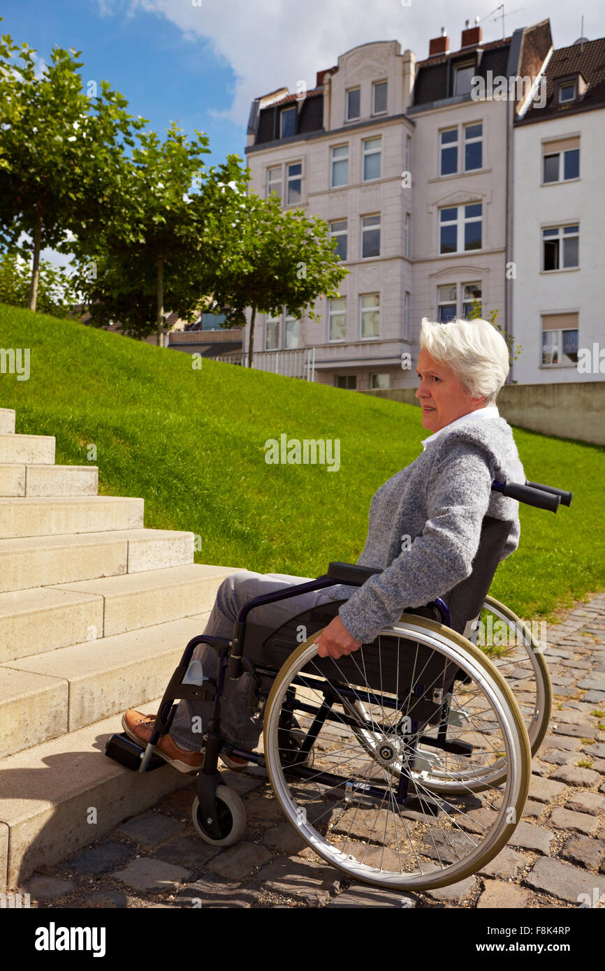 Ältere Frau im Rollstuhl Blick auf Treppe Stockfoto