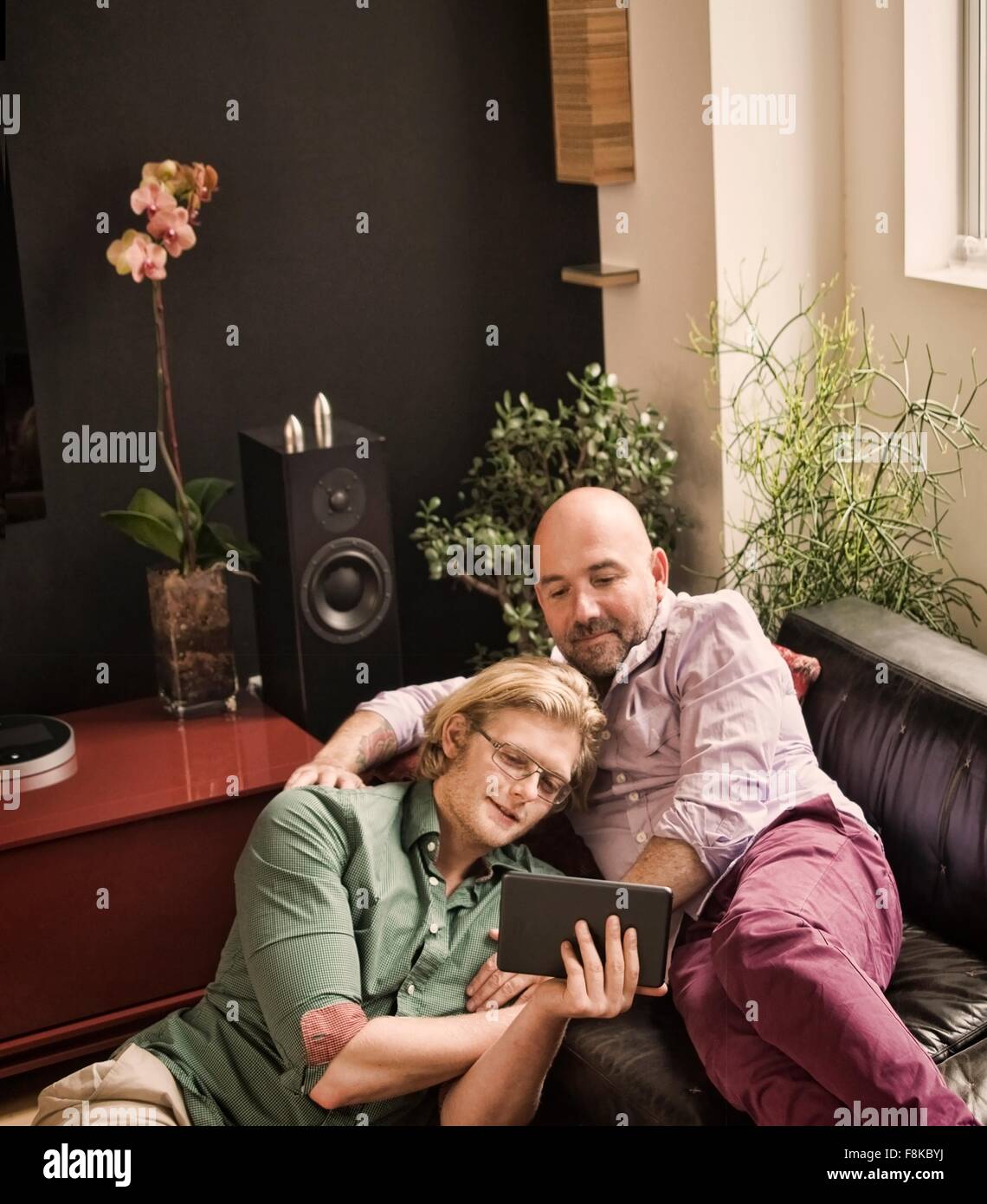 Männlichen Partner liegend auf Sofa Blick auf digital-Tablette Stockfoto