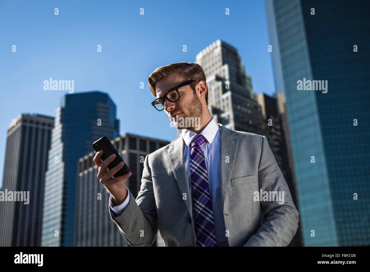 Junger Geschäftsmann vor Bürogebäude lesen Smartphone Texte, New York, USA Stockfoto