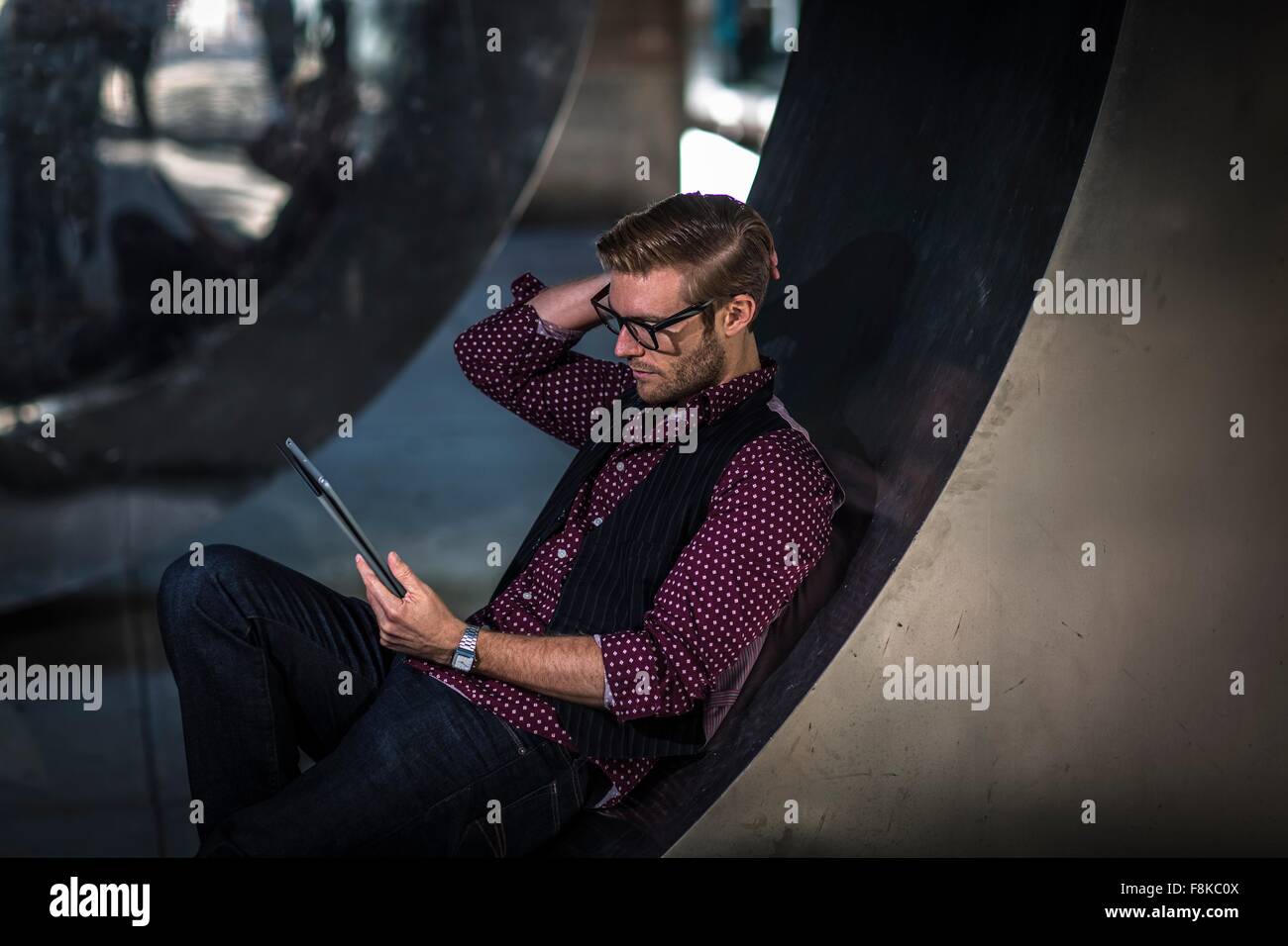 Junger Geschäftsmann liegend auf gebogenen Wand lesen digital-Tablette Stockfoto