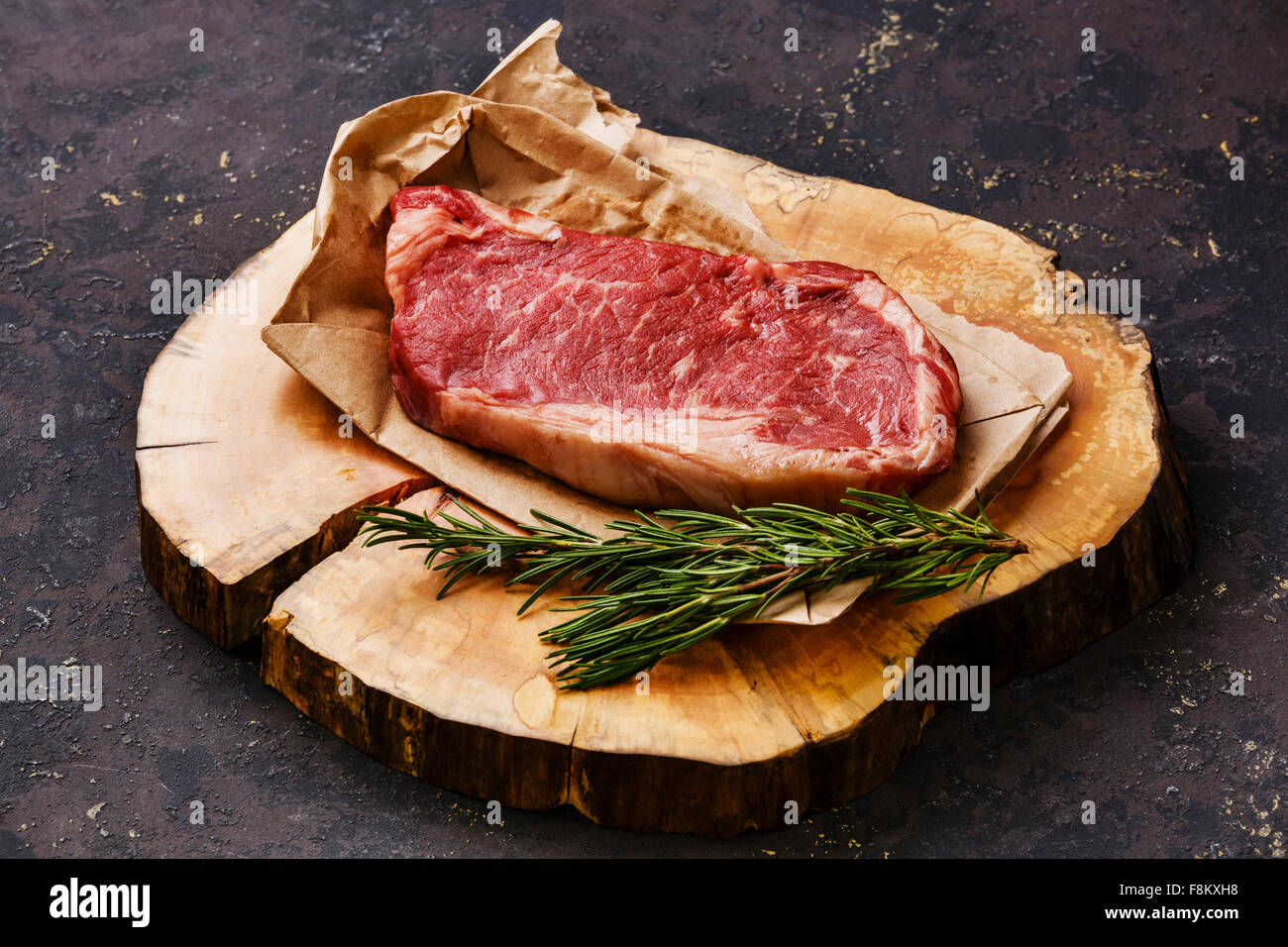Rohes Frischfleisch Striploin Steak auf Butcher-Block auf dunklem Hintergrund Stockfoto