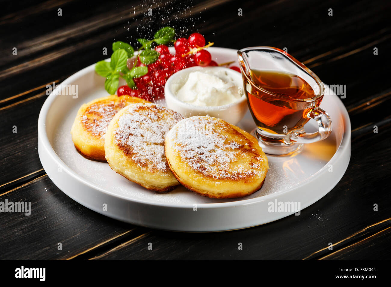Braten, hausgemachter Hüttenkäse Pfannkuchen russische Syrniki mit roten Johannisbeeren auf weißen Teller Stockfoto