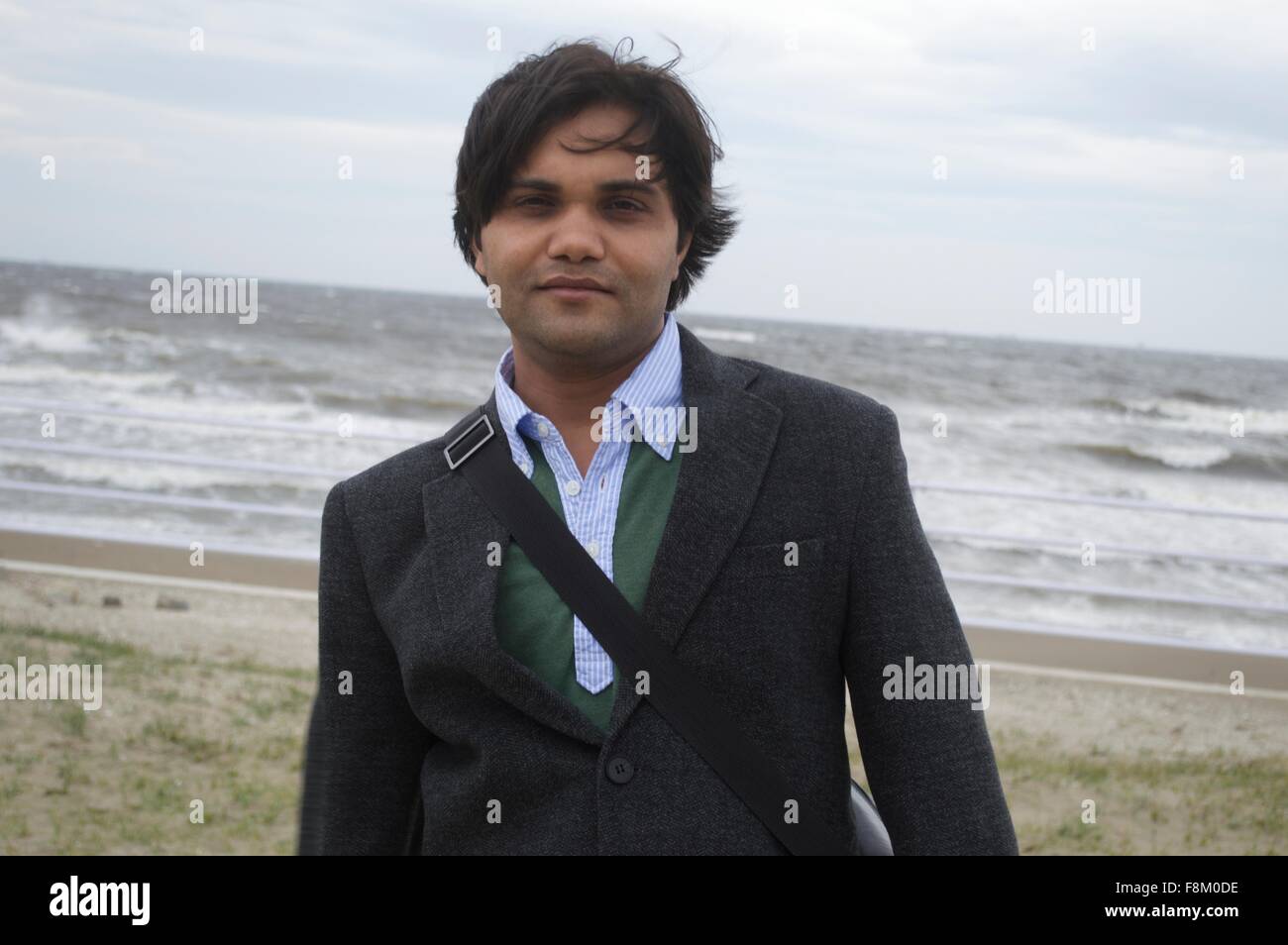 Ein Geschäftsmann am Strand in der Nähe von Meer mit starkem wind Stockfoto
