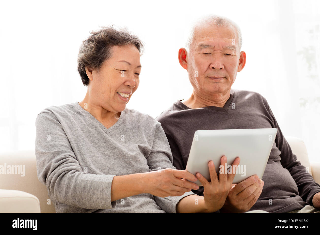 Senior-Hochzeitspaar beobachten die Tablette auf sofa Stockfoto