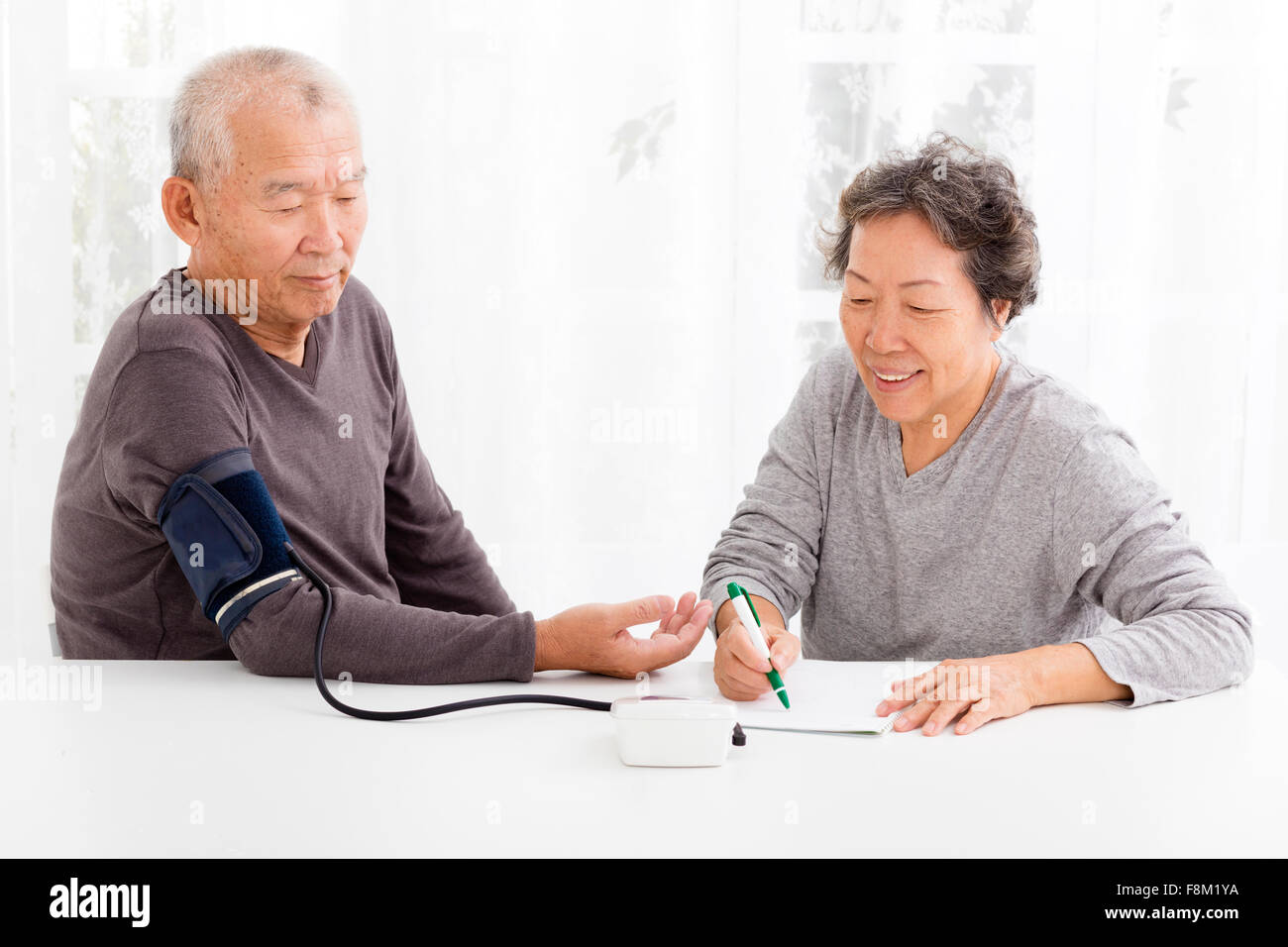 gerne älteres Paar die Blutdruckmessung im Wohnzimmer Stockfoto