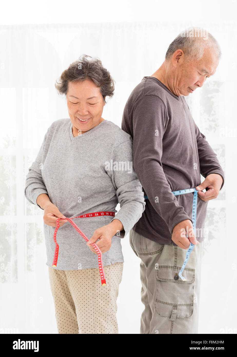 asiatische älteres paar Bauch mit Maßband messen Stockfoto